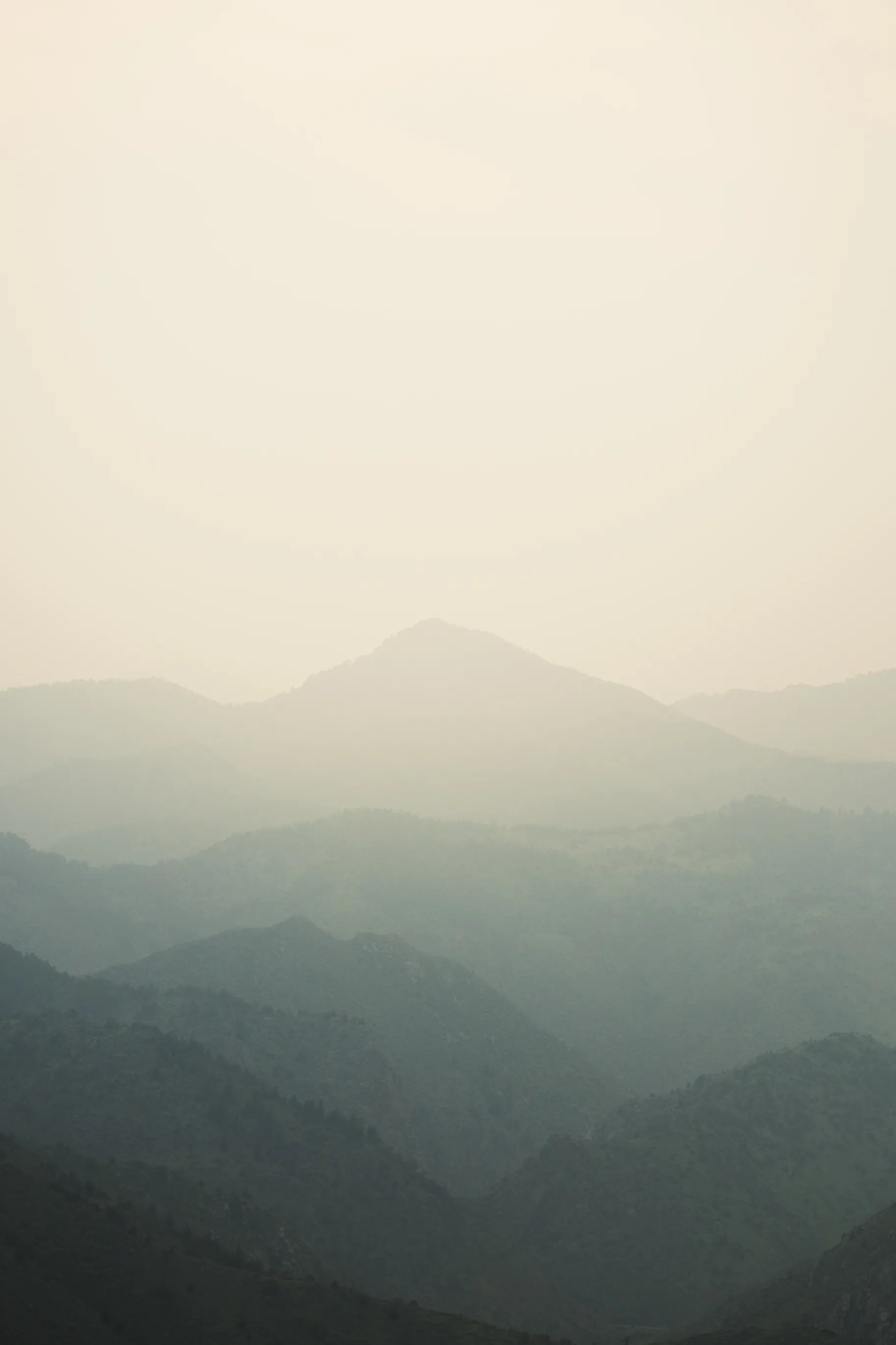 Mountain ridges fading in layers into a pale, hazy sky