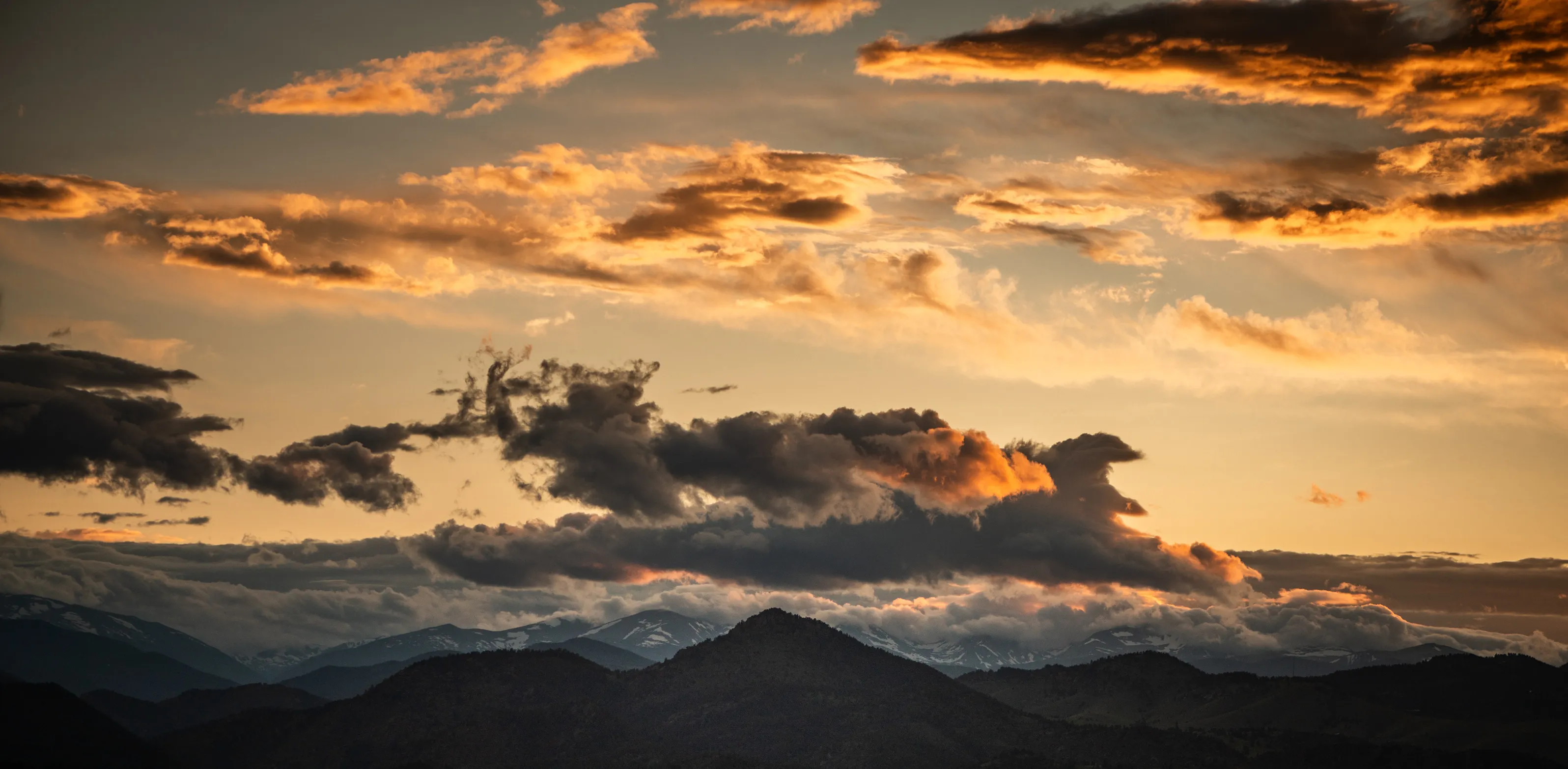 Golden sunset clouds above a silhouetted mountain range
